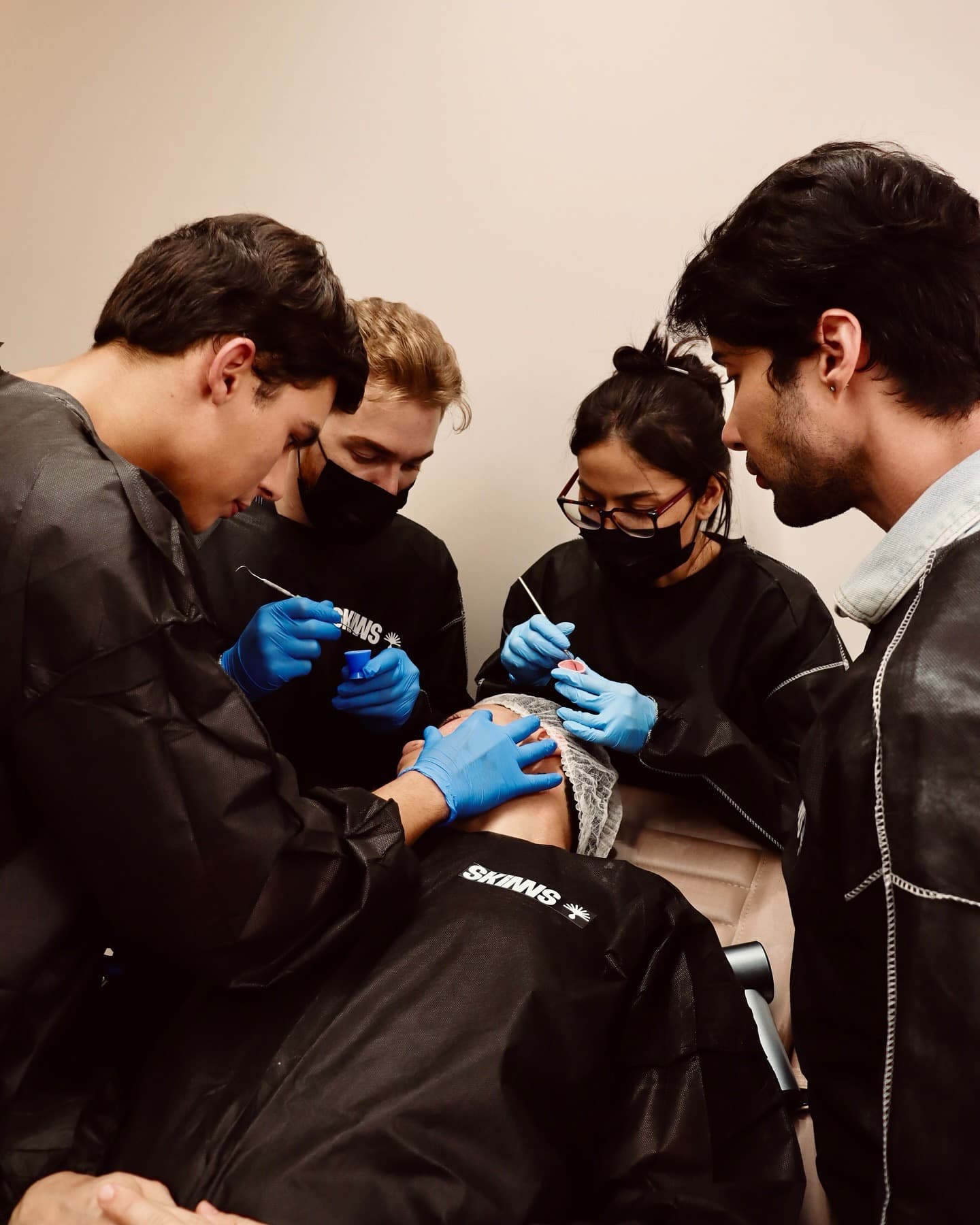 Grupo de alunos aplicando peeling juntos em paciente real